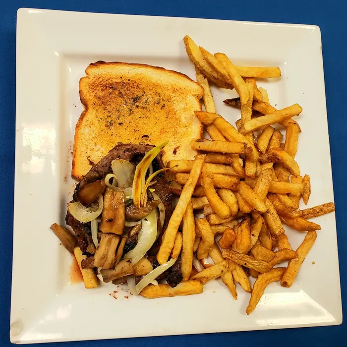 Steak sandwich on garlic toast with sautéed onions and mushrooms, served with fries